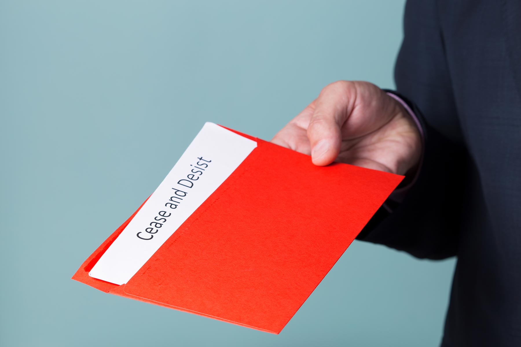 A lawyer holding a red envelope containing a cease and desist letter
