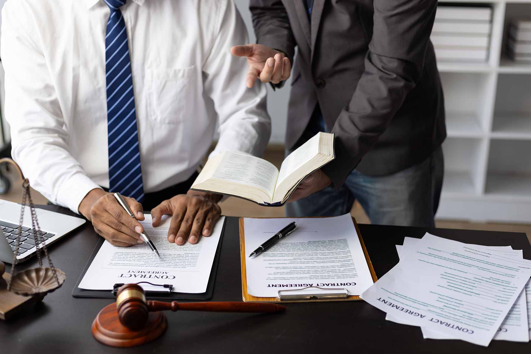 A paralegal and a lawyer reviewing and discussing a legal contract at the office A paralegal and a lawyer reviewing and discussing a legal contract at the office